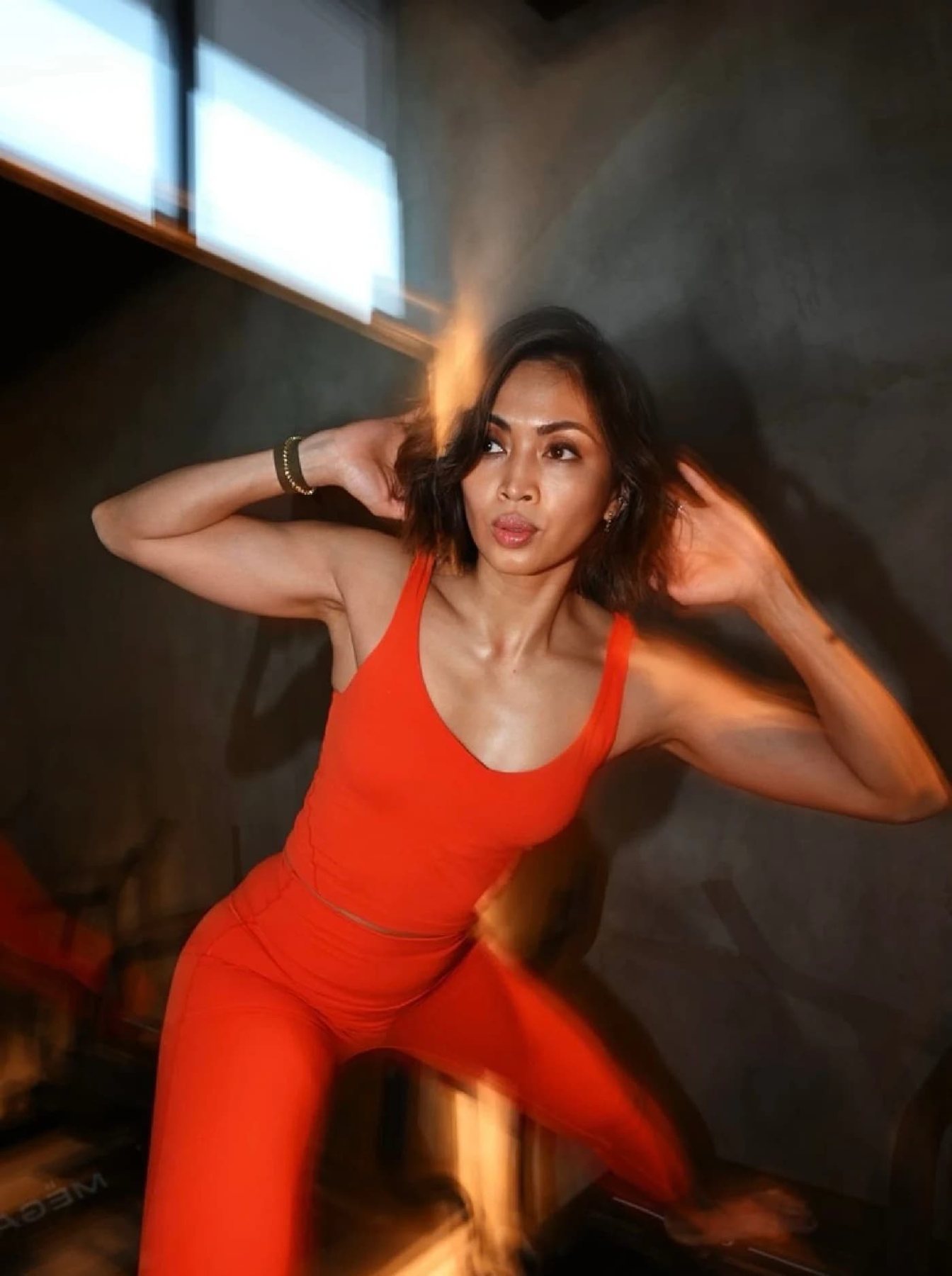 Ciarra Kindl in an orange training outfit posing with hands behind her head